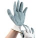 A pair of hands wearing Cordova white gloves with blue and gray accents.