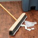 A Carlisle 24" push broom head with gray flagged bristles on the floor.