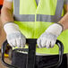 A person wearing Cordova Standard Grain Cowhide Driver's Gloves and a safety vest holding a forklift.