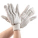 A pair of hands wearing white Cordova Economy Weight work gloves.