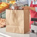 A woman holding a Duro paper shopping bag with food inside.