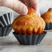 A hand placing a mini fluted brioche into a grey Matfer Bourgeat mini brioche mold.