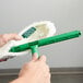 A hand holding a green Unger StripWasher with a white cloth.