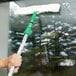 A hand using a Unger StripWasher with a green handle to clean a window.