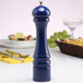 A Chef Specialties cobalt blue salt mill on a table with food.