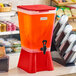 A red 5-gallon beverage dispenser filled with fruit punch and equipped with a spigot.