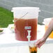 A person using a Choice clear plastic beverage dispenser to pour a drink.