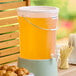 A large clear round beverage dispenser filled with fruit punch, featuring a spigot and a handle.