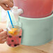 A hand pouring a drink into a glass jar on a counter.