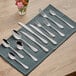 A close-up of Acopa Benson stainless steel dinner forks on a table with a blue cloth and napkins.