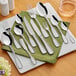 A set of Acopa stainless steel demitasse spoons on a table with a napkin