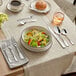 A table with a bowl of salad and Acopa Scottdale extra heavy weight teaspoons.