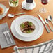 A silver fork on a table with food and a drink.