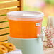 A 3-gallon clear round beverage dispenser filled with orange fruit punch and equipped with a white spigot.