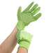 A pair of hands wearing lime green Cordova warehouse gloves with black dots.