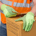 A man wearing Cordova lime green warehouse gloves with black dots holding a box.