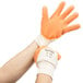 A pair of hands wearing orange Cordova Ruffian warehouse gloves.