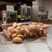 A Cambro red polycarbonate food storage box on a table filled with potatoes.