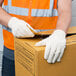 A man wearing Cordova medium weight canvas work gloves and a safety vest holding a box.