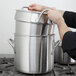A person holding a large metal pot.
