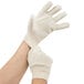 A pair of hands wearing white Cordova canvas work gloves.