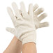 A pair of hands wearing Cordova white canvas work gloves.