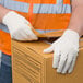 A person wearing Cordova standard weight polyester/cotton canvas work gloves opening a box.