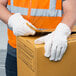 A person wearing Cordova Natural Nap-Out work gloves and holding a box.