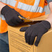 A person wearing Cordova brown jersey gloves holding a box with a label.