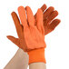 A hand wearing orange Cordova canvas work gloves with black PVC dots.