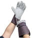 A pair of hands wearing Cordova striped canvas work gloves with leather palm coating and rubber cuffs with a gray and red stripe.