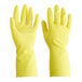 A close-up of a pair of yellow Cordova latex rubber gloves with a finger up.