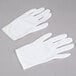 A pair of white Cordova Inspector's gloves on a gray surface.