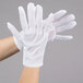 A person wearing Cordova white nylon inspection gloves.