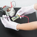 A person wearing Cordova Women's white inspector's gloves holding a circuit board.