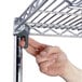 A hand adjusting a metal shelf on a Metro wire shelving unit.