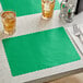 A table set with a green scalloped paper placemat and two glasses of ice tea.