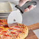 A person using a pizza cutter to cut a pizza.