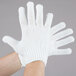 A pair of hands wearing Cordova white polyester work gloves.