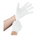 A pair of white polyester work gloves being worn on hands.