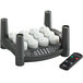 A black and white candle holder with a black remote control with red, green, and blue buttons holding six white flameless tea lights.