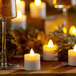 A lit Sterno flameless tea light on a table with wine glasses.