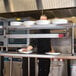 A chef using an Avantco high wattage strip warmer on a counter in a school kitchen.