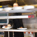 A man using an Avantco high wattage strip warmer to heat a plate of food.