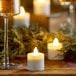 A wood table with a glass of wine and white Sterno flameless tea lights.