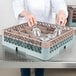 A woman using a Noble Products glass rack to wash glasses in a dishwasher.