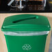 A Lavex green slim rectangular recycling trash can lid on a green recycling bin.