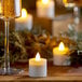 A glass of champagne next to amber Sterno flameless tea lights on a wood surface.