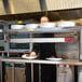 A man using an Avantco high wattage strip warmer on a counter in a kitchen.