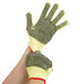 A close-up of a gloved hand wearing Cordova Aramid / Cotton Grip Gloves with PVC Dotted Coating.